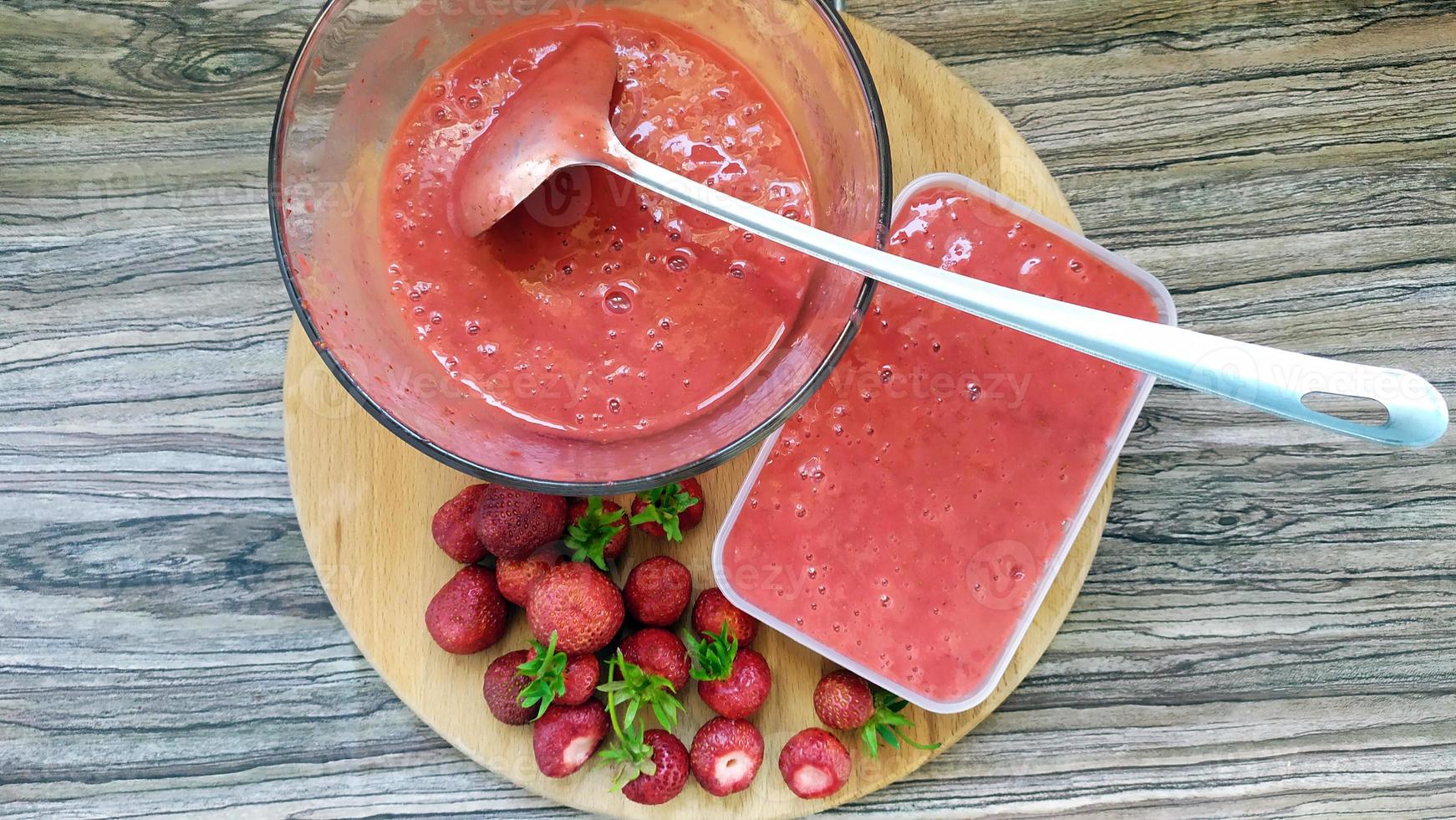 des fraises entières reposent sur une planche à découper. bol en verre avec des fruits photo