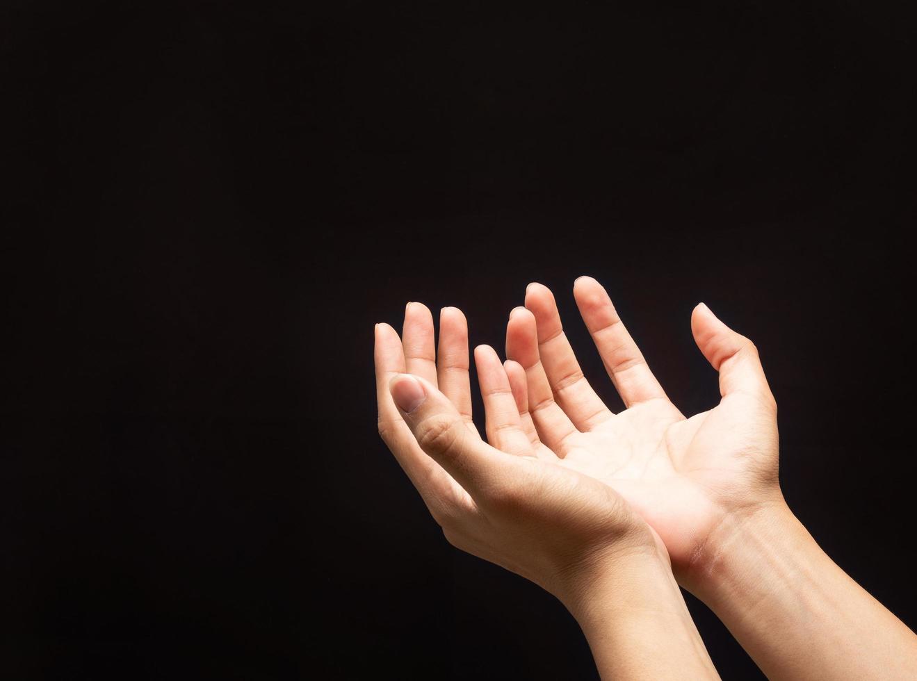 les mains en prière sur fond noir photo