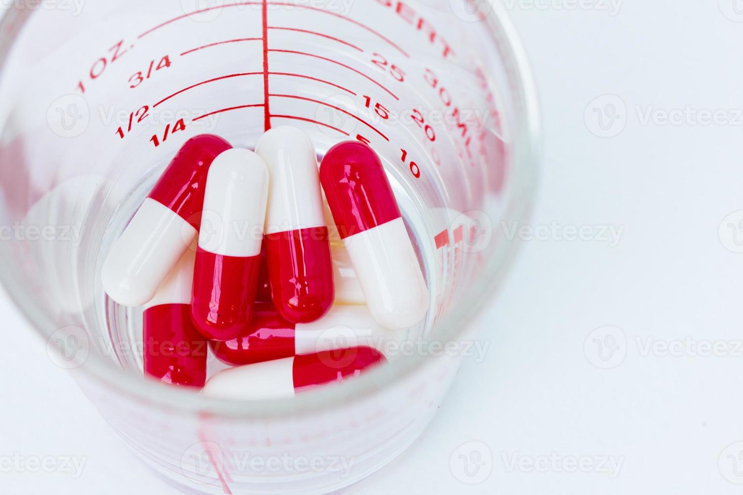 capsules rouges blanches dans une tasse de verre photo