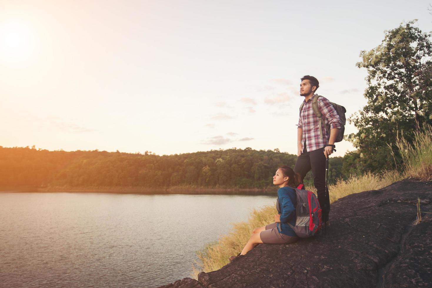 couple se reposant au sommet de la montagne sous le lac pendant le coucher du soleil. photo