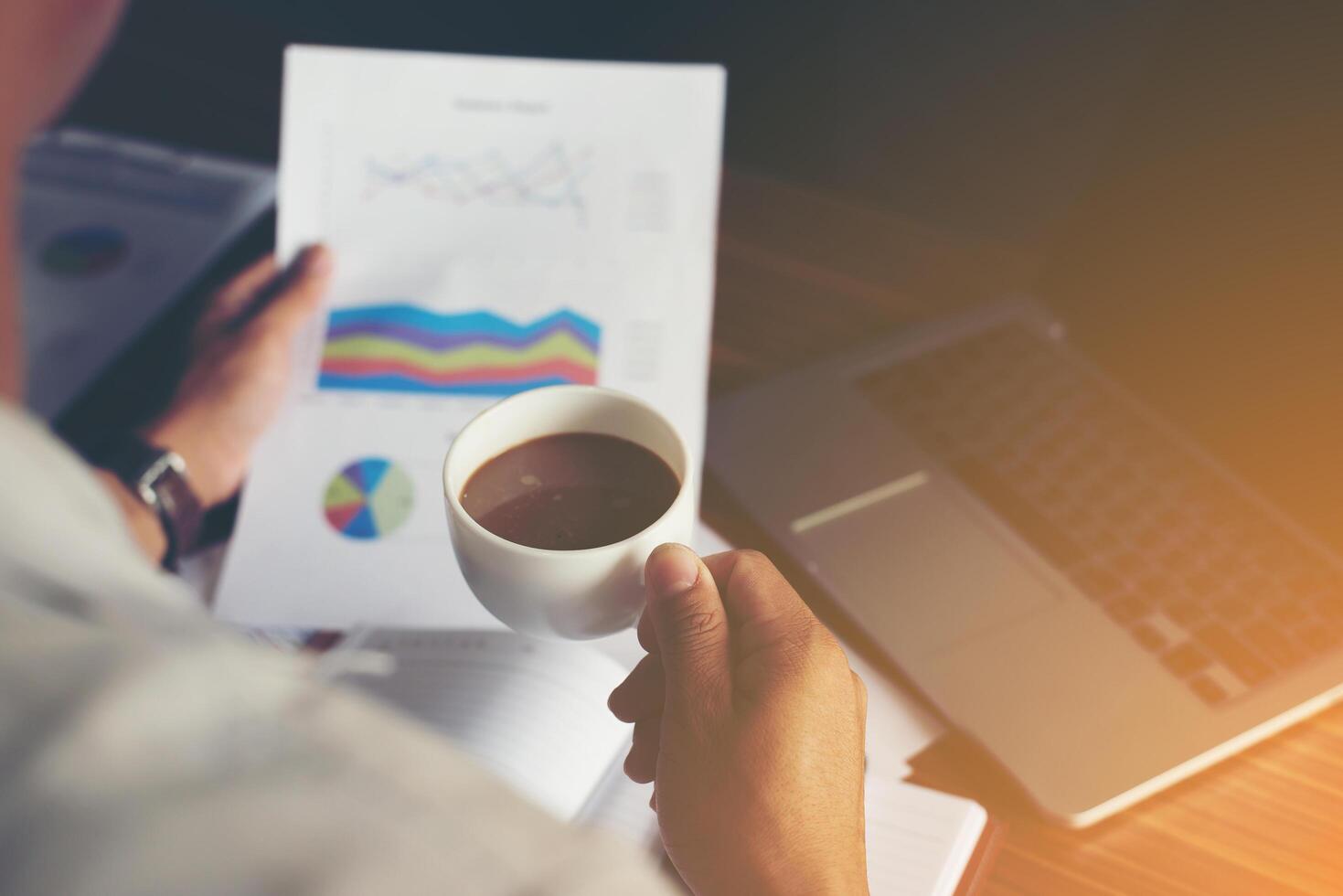 homme d'affaires analyse graphique financier et tenant une tasse de café. photo