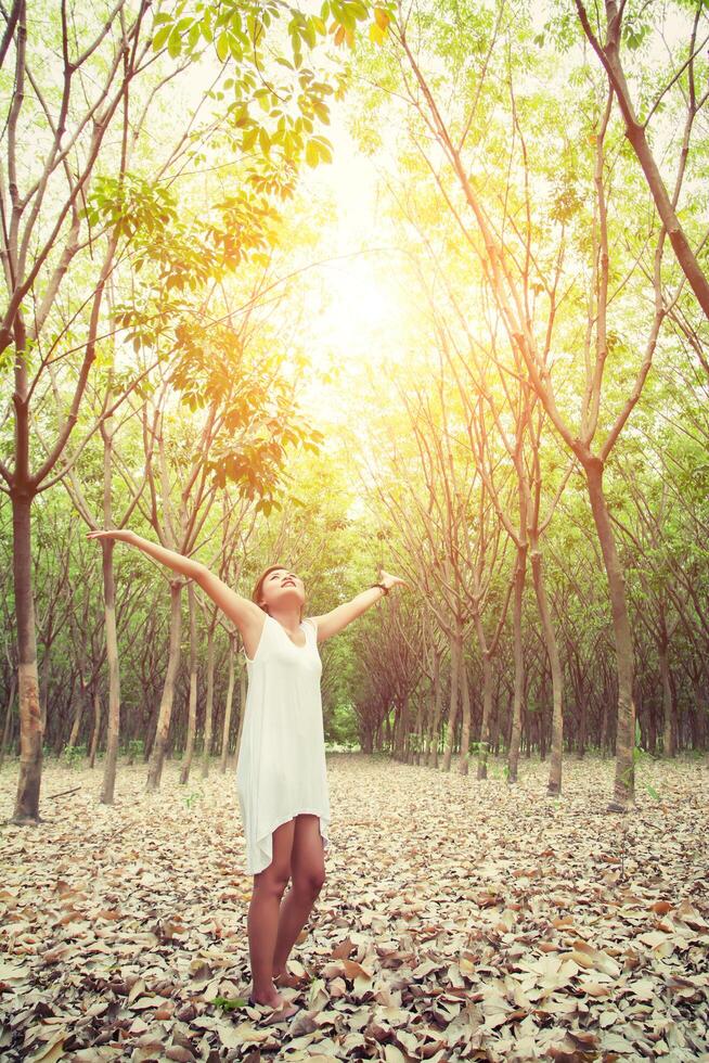 belle jeune femme a levé les bras en profitant de la fraîcheur dans la forêt verte. photo