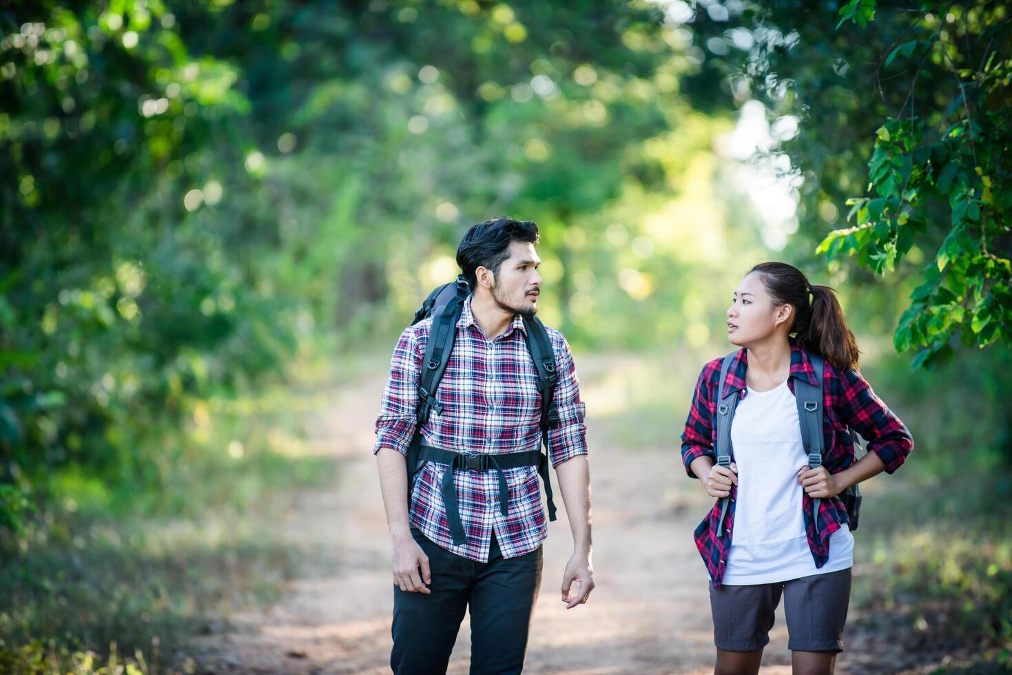 jeune couple marchant avec des sacs à dos en forêt. randonnées aventure. photo