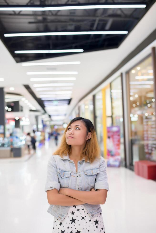 belle jeune femme debout pensant quelque chose au centre commercial. photo