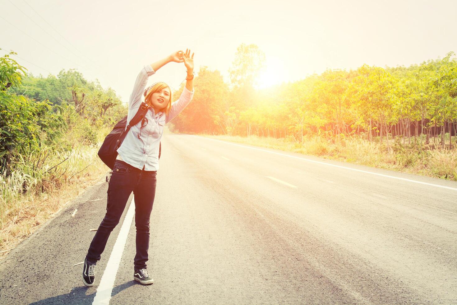 femme hipster faisant de l'auto-stop sur une route de campagne à la recherche de la voiture photo