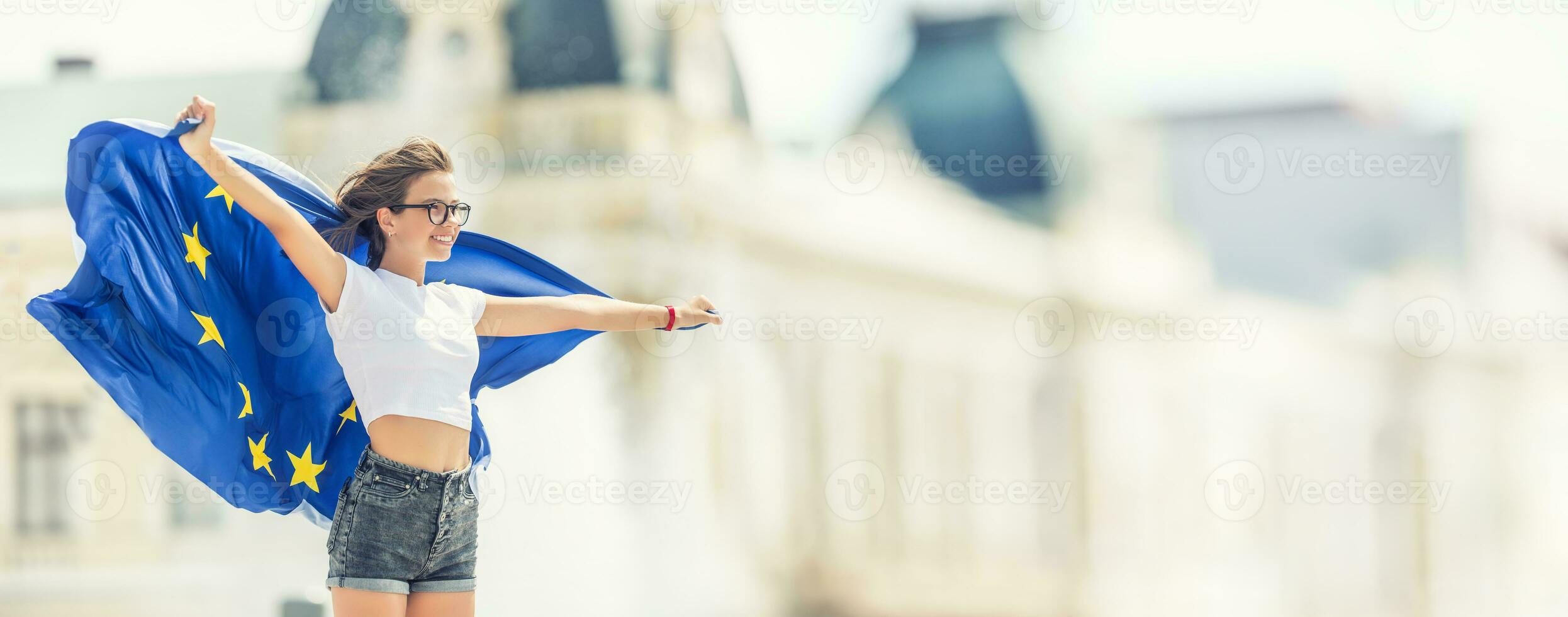 mignonne content Jeune fille avec le drapeau de le européen syndicat dans de face de une historique bâtiment quelque part dans L'Europe . photo