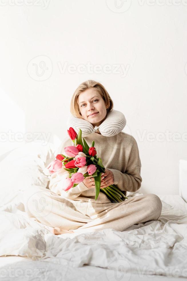 femme endormie assise dans son lit portant un pyjama et un oreiller sur le cou photo