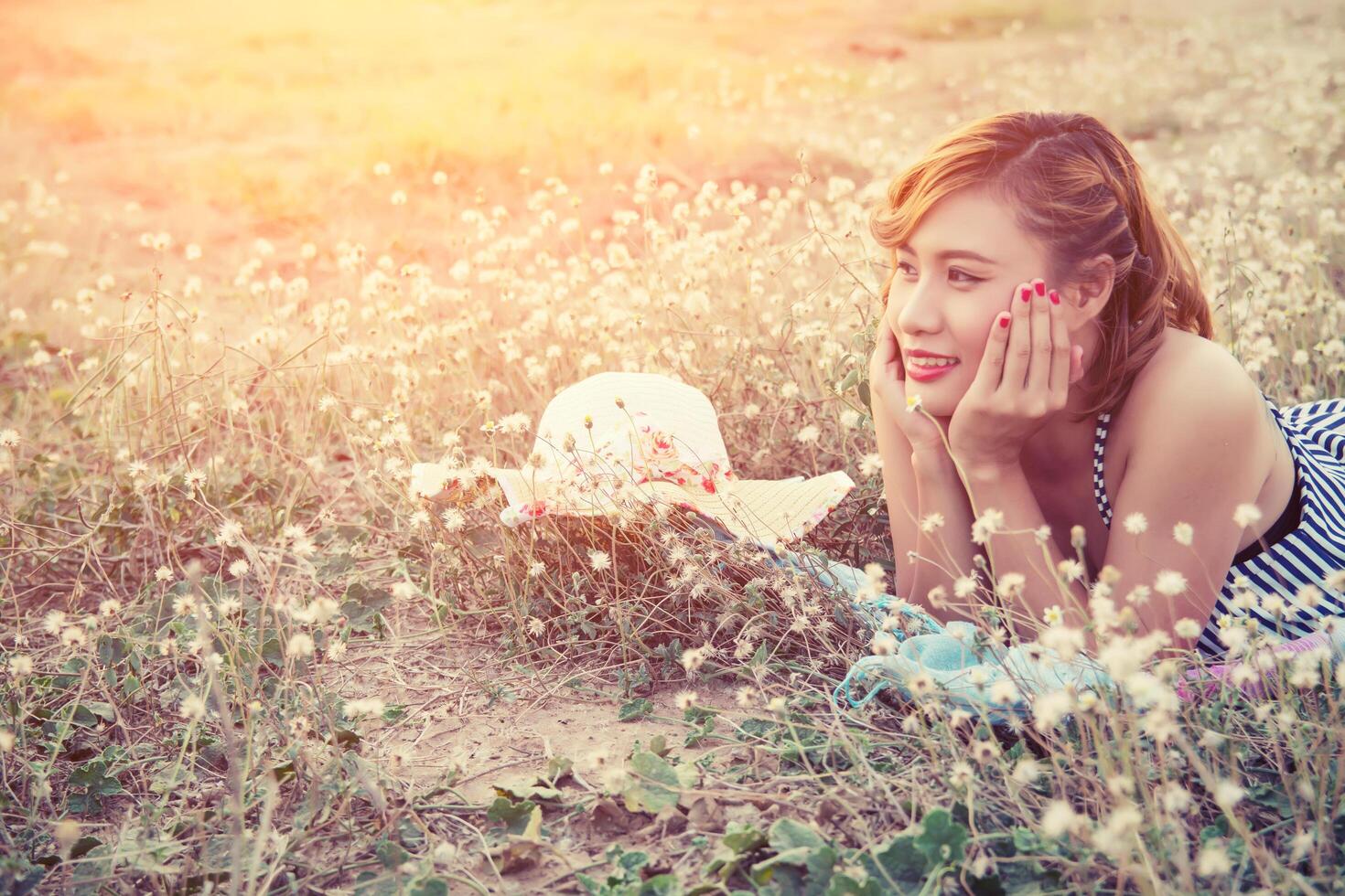 jeune femme sexy se reposant sur le champ de fleurs et souriant photo