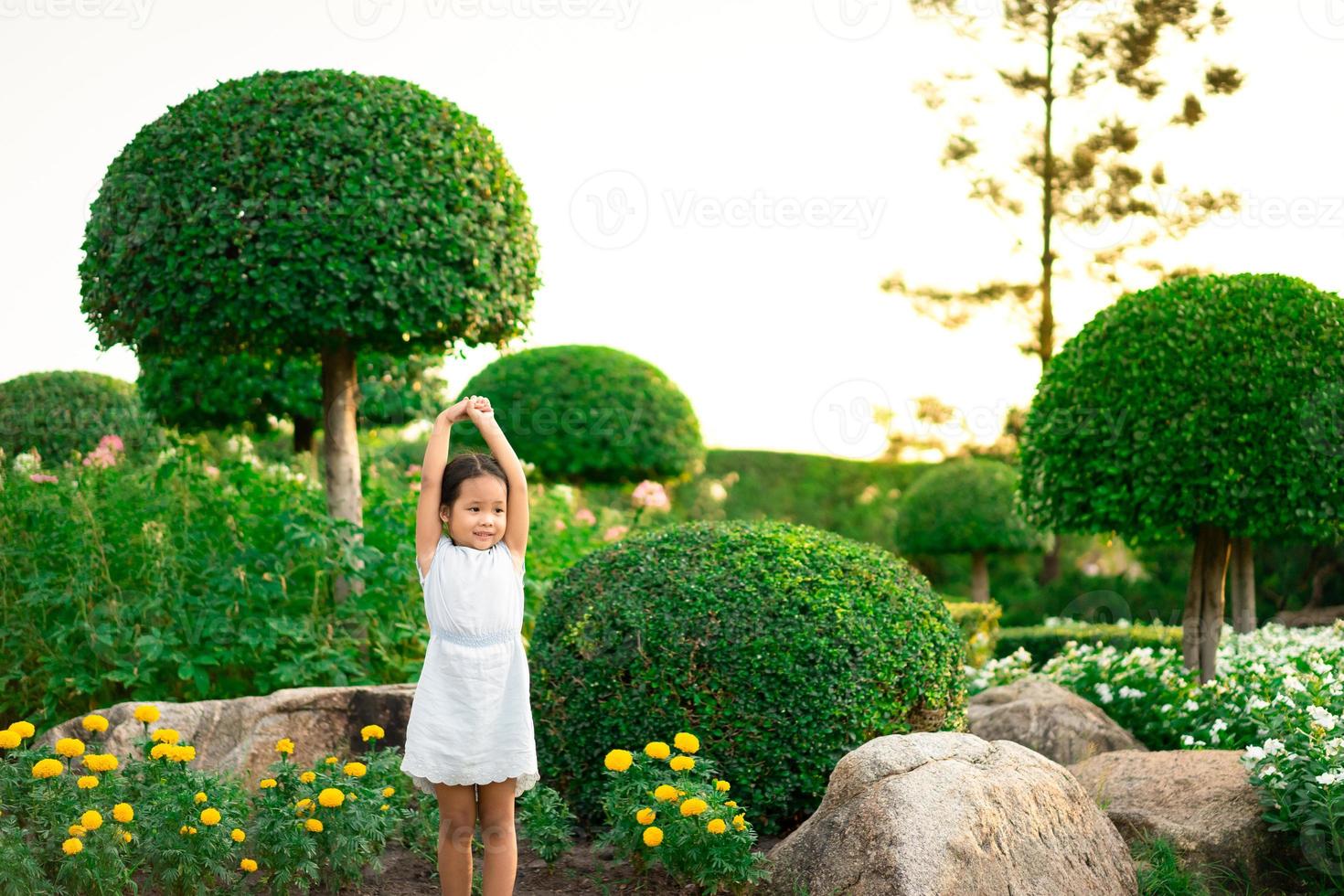 petite fille debout sur le rocher et mains ouvertes avec le coucher du soleil photo