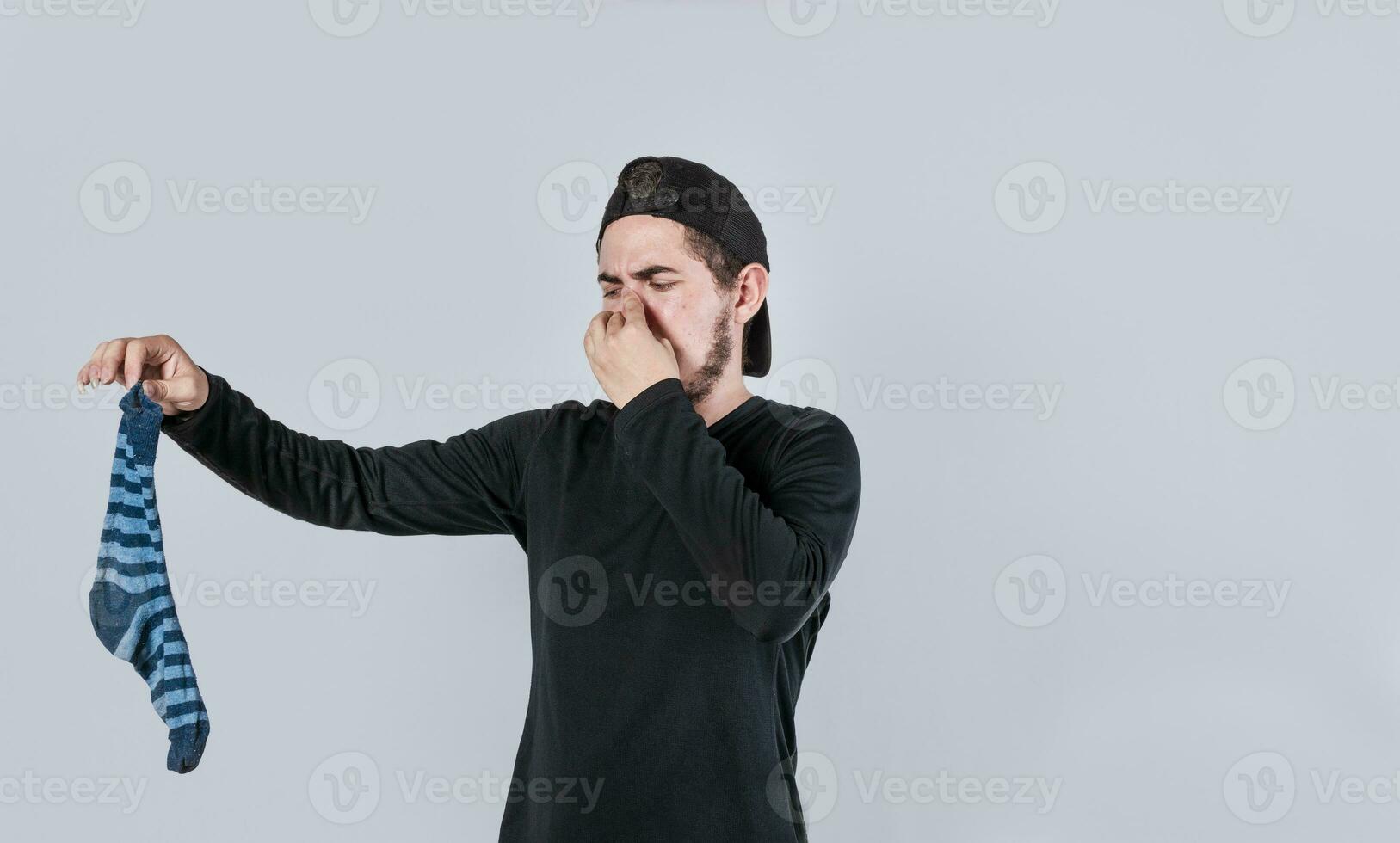 une homme avec une chaussette dans le sien main couvrant le sien nez, une gars avec une puant chaussette dans le sien main, malodorant chaussettes concept photo