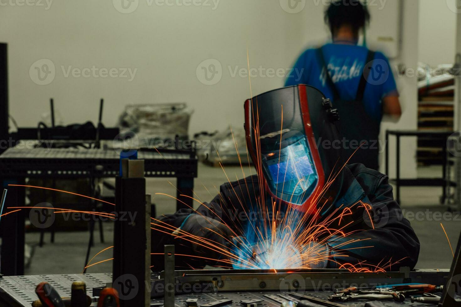 soudeur professionnel de l'industrie lourde travaillant à l'intérieur de l'usine, porte un casque et commence à souder. mise au point sélective photo