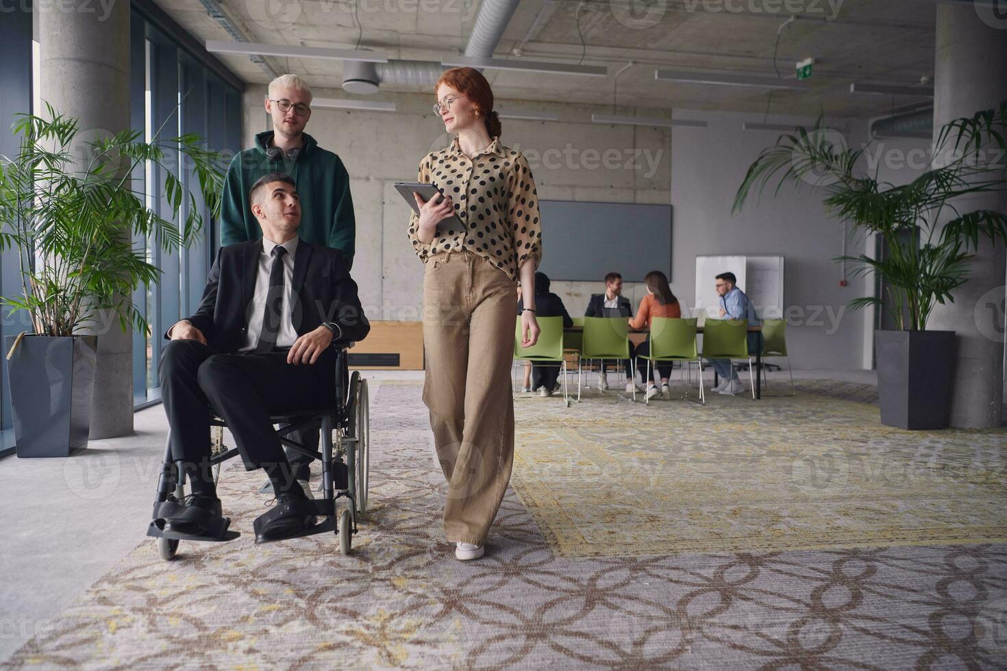 une groupe de affaires collègues dans une moderne Bureau illustre inclusivité et soutien comme elles ou ils avec compassion roue leur affaires ami dans une fauteuil roulant, mettant en valeur travail en équipe et responsabilisation dans le lieu de travail. photo