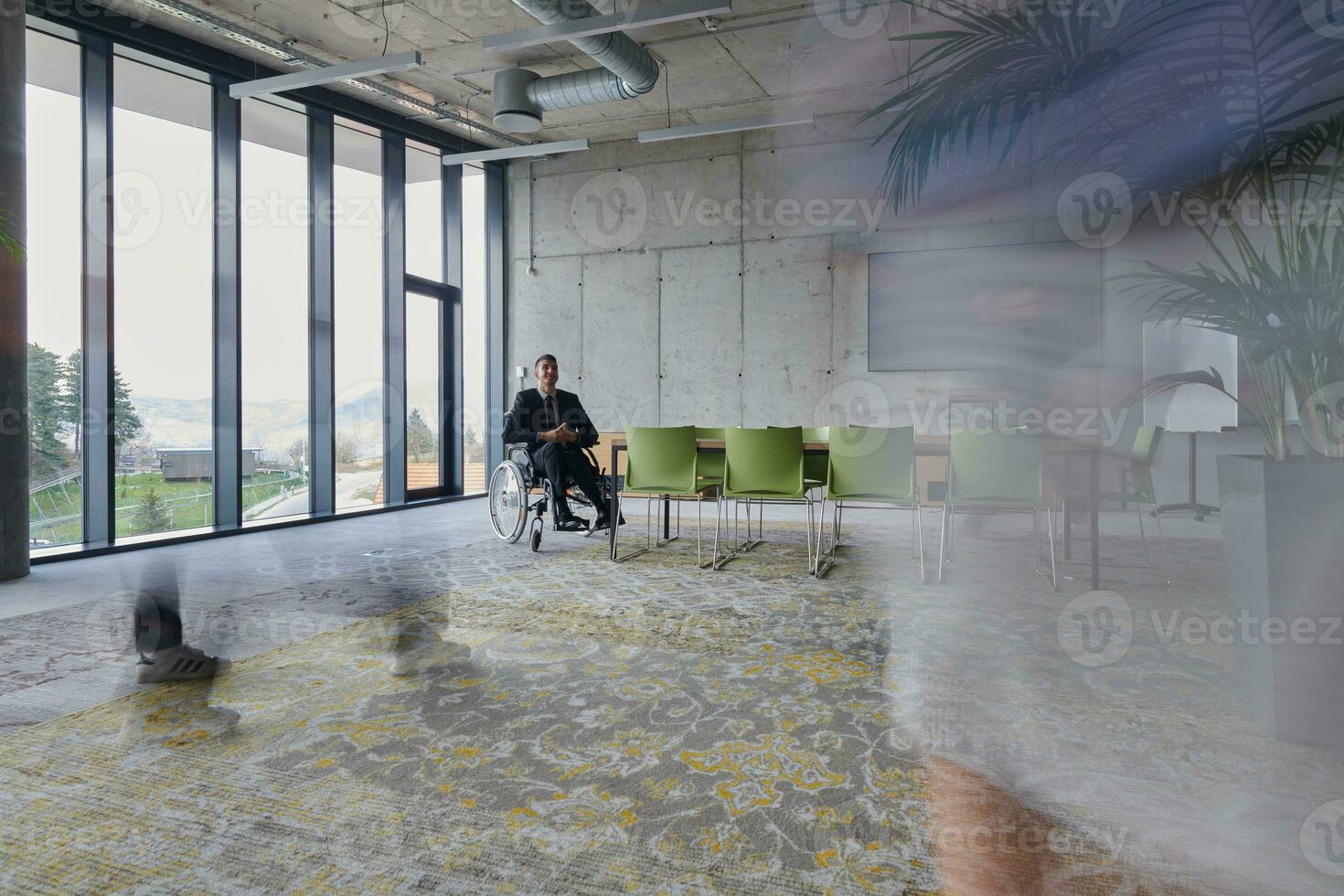 une homme d'affaire dans une fauteuil roulant est assis à une table dans une grand, moderne bureau, tandis que le sien collègues recueillir autour, leur pas flou, symbolisant inclusivité, soutien, et unité dans le visage de défis. photo