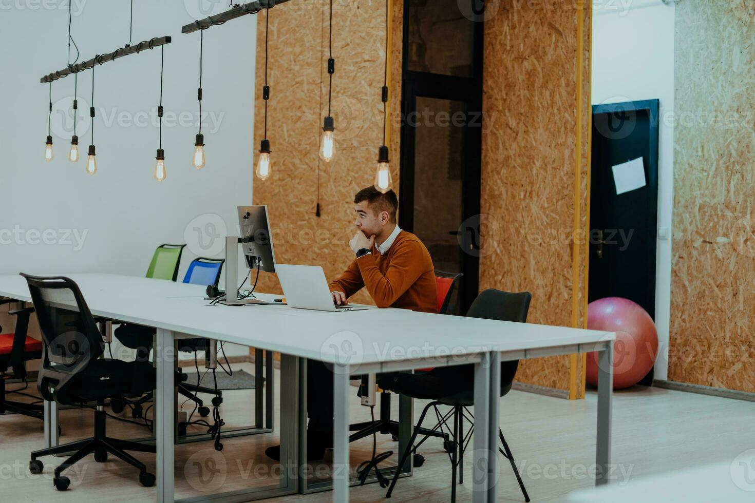 homme d'affaires multitâche travaillant au bureau. il utilise le pavé tactile tout en lisant un e-mail sur un ordinateur portable et en prenant des notes sur le papier. photo