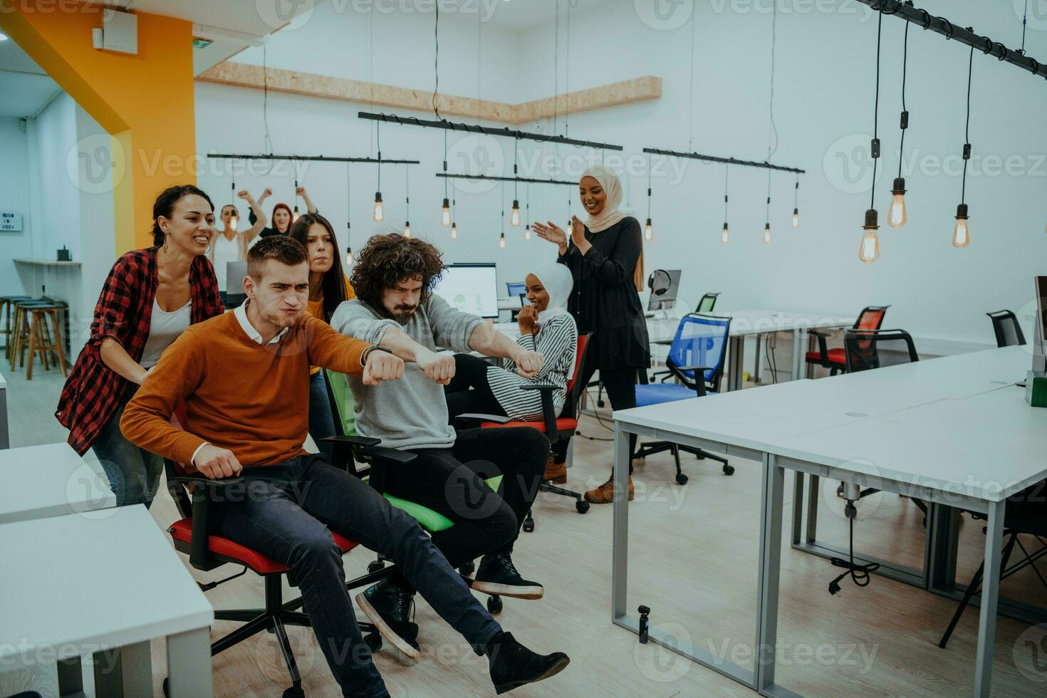 équipe bâtiment et Bureau amusement. Jeune de bonne humeur hommes d'affaires dans intelligent décontractée porter ayant amusement tandis que courses sur Bureau chaises et souriant. photo