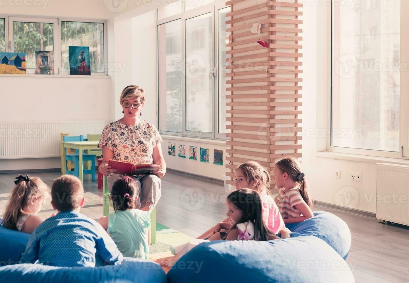 en train de lire temps dans élémentaire école ou Jardin d'enfants, prof en train de lire une livre à des gamins dans élémentaire école ou maternelle. sélectif concentrer photo