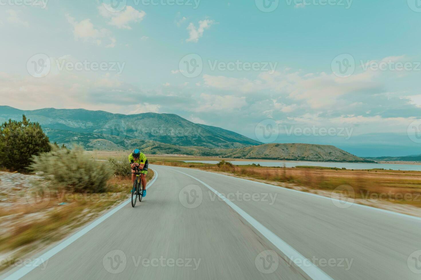 plein longueur portrait de un actif triathlète dans tenue de sport et avec une protecteur casque équitation une vélo. sélectif concentrer photo