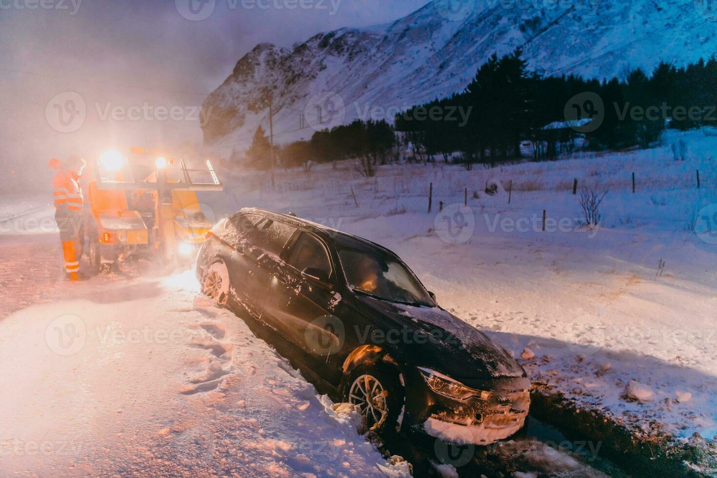 le bord de la route assistance un service tirant le voiture en dehors de le canal. un incident sur une congelé scandinave route. photo