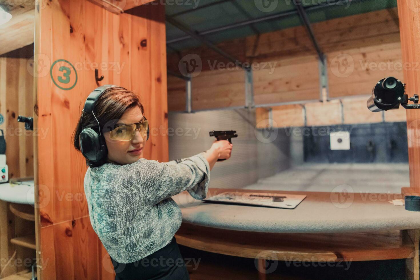 une femme les pratiques tournage une pistolet dans une tournage intervalle tandis que portant protecteur écouteurs photo