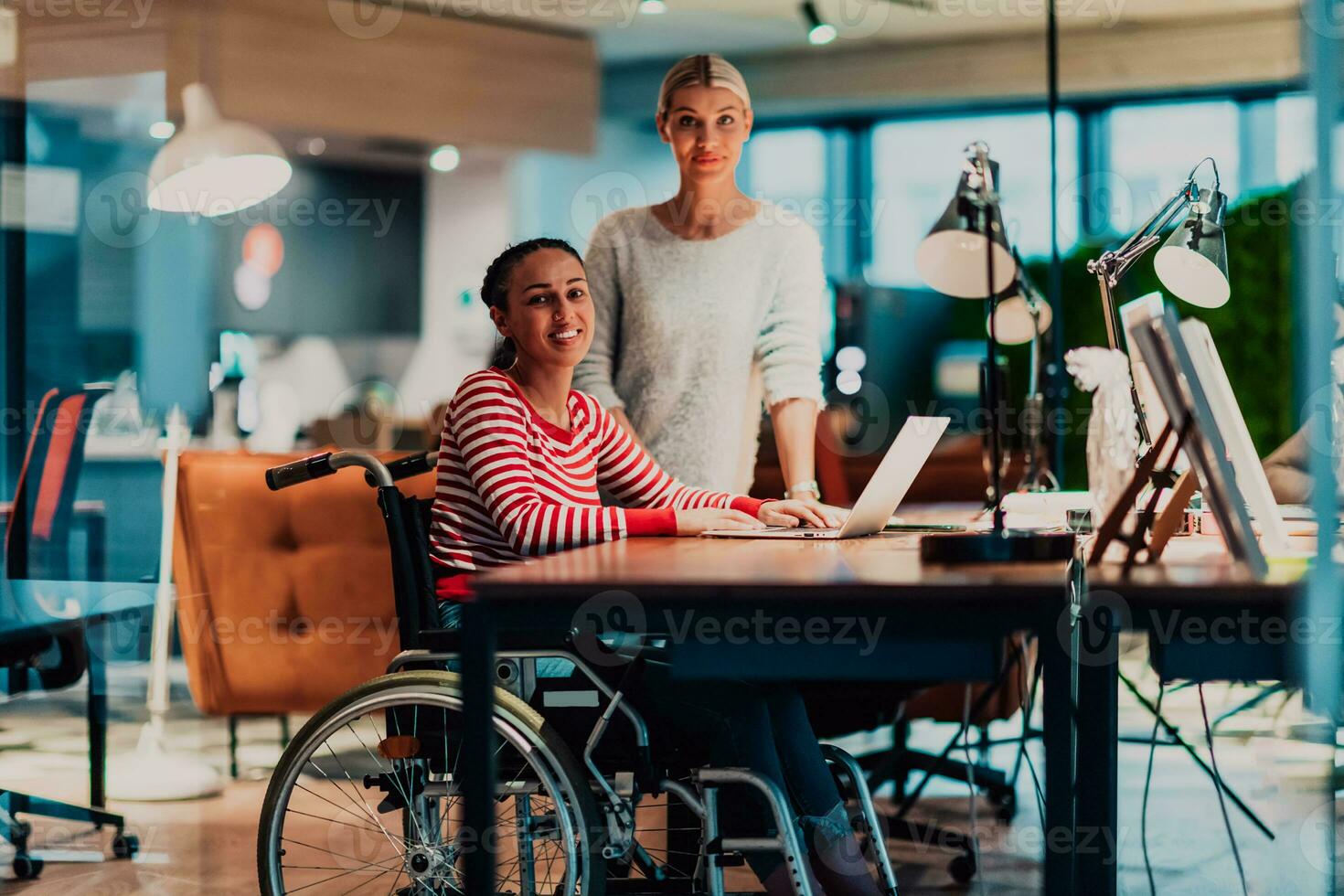 femme d'affaires dans une fauteuil roulant travail dans une Créatif bureau. affaires équipe dans moderne cotravail Bureau espace. collègues travail dans le Contexte à en retard nuit. photo