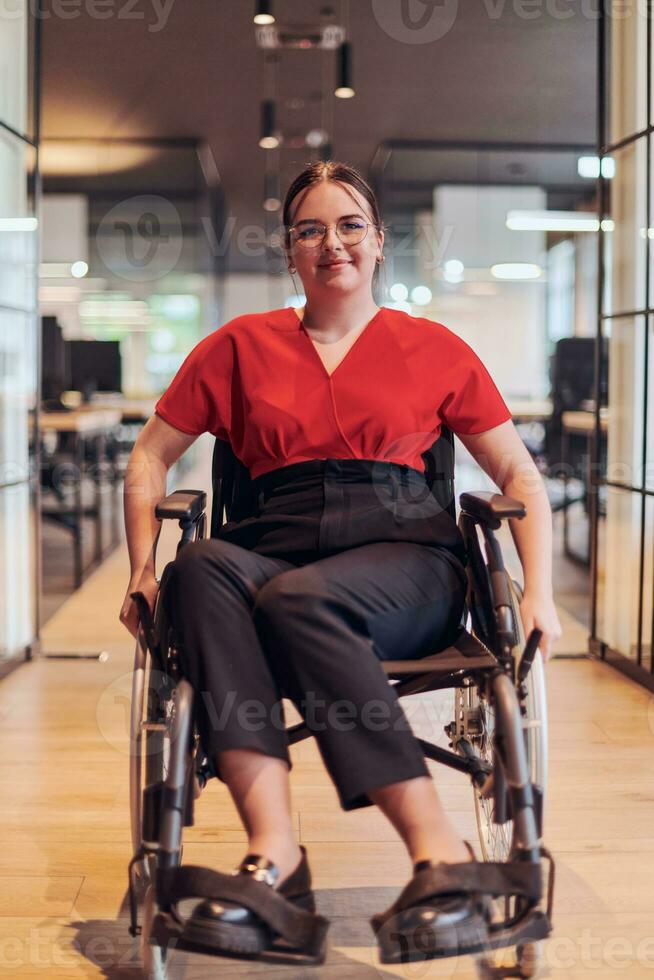 une moderne Jeune femme d'affaires dans une fauteuil roulant est entouré par un compris espace de travail avec aux parois de verre des bureaux, incorporant détermination et innovation dans le affaires monde photo