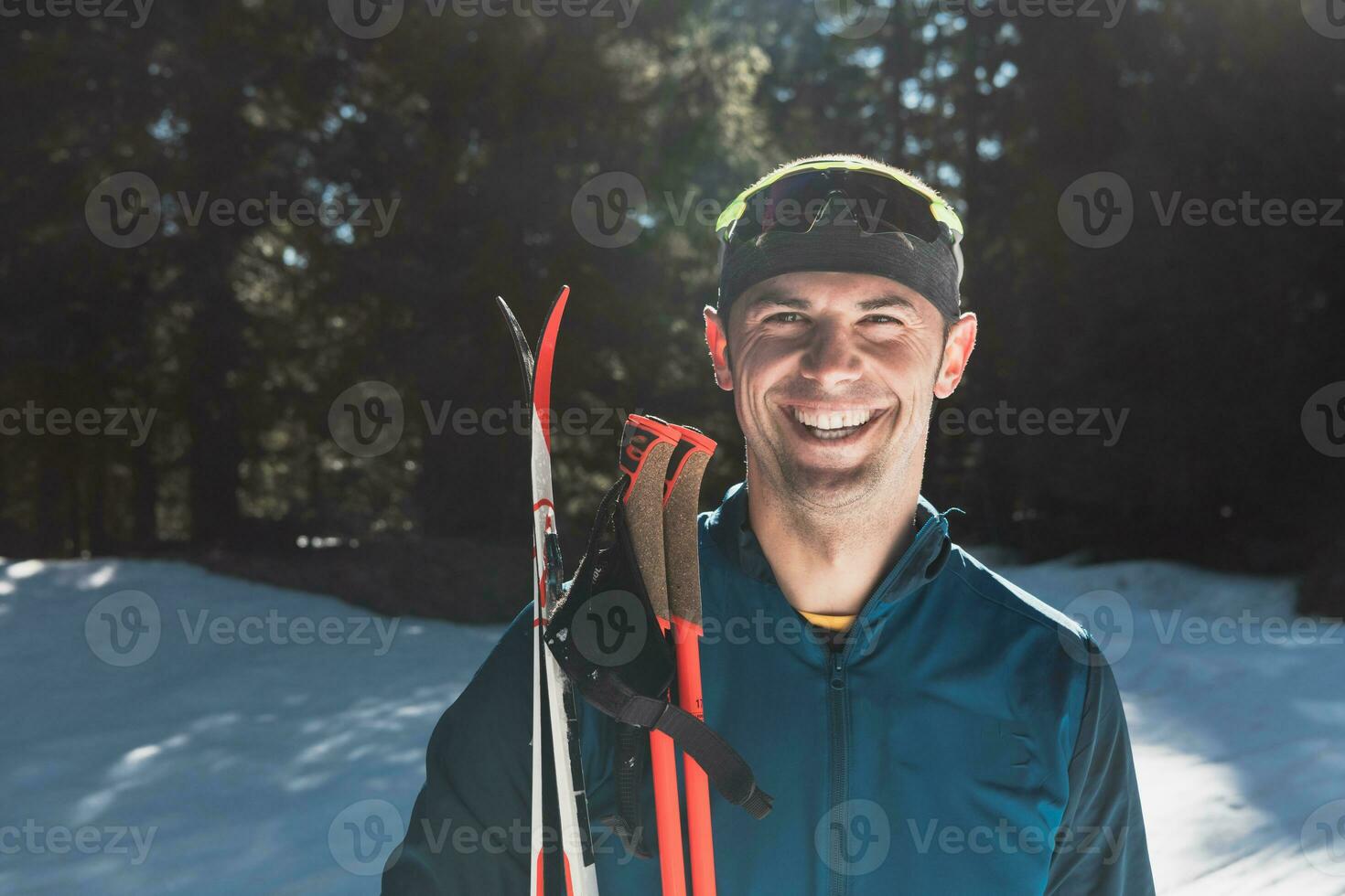 portrait Beau Masculin athlète avec traverser pays des skis dans mains et des lunettes de protection, formation dans neigeux forêt. en bonne santé hiver mode de vie concept. photo