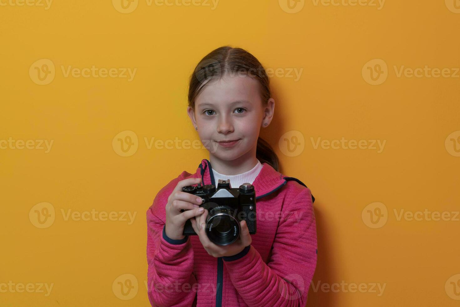 peu fille photographe isolé sur Jaune Contexte souriant prise Photos avec une rétro ancien caméra.