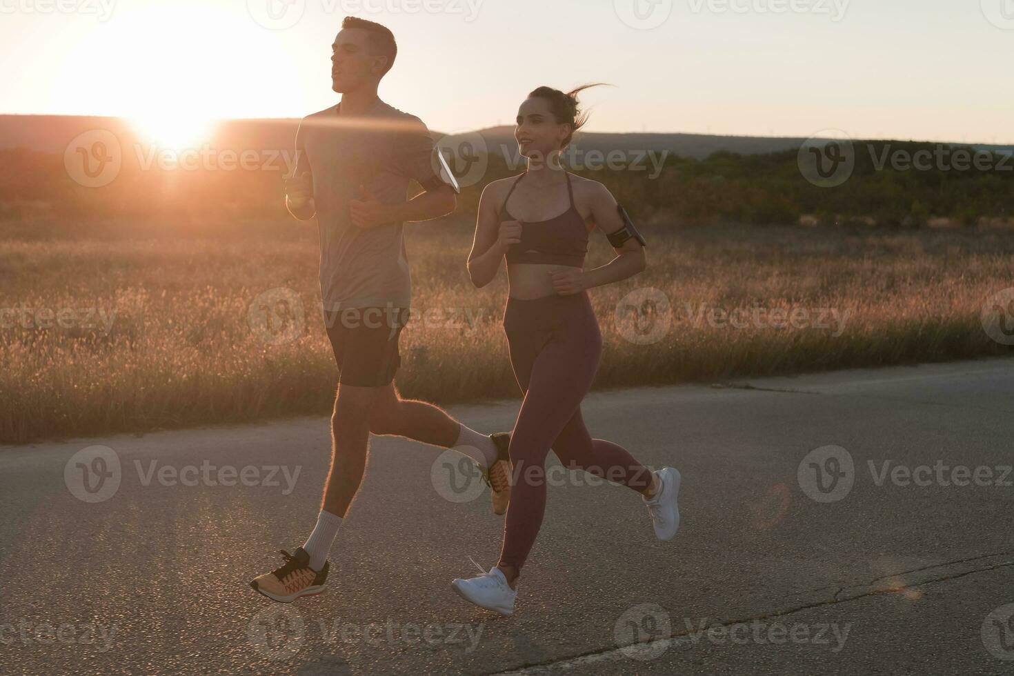 en bonne santé Jeune couple le jogging dans le ville des rues dans le de bonne heure Matin avec une magnifique lever du soleil dans le Contexte. photo