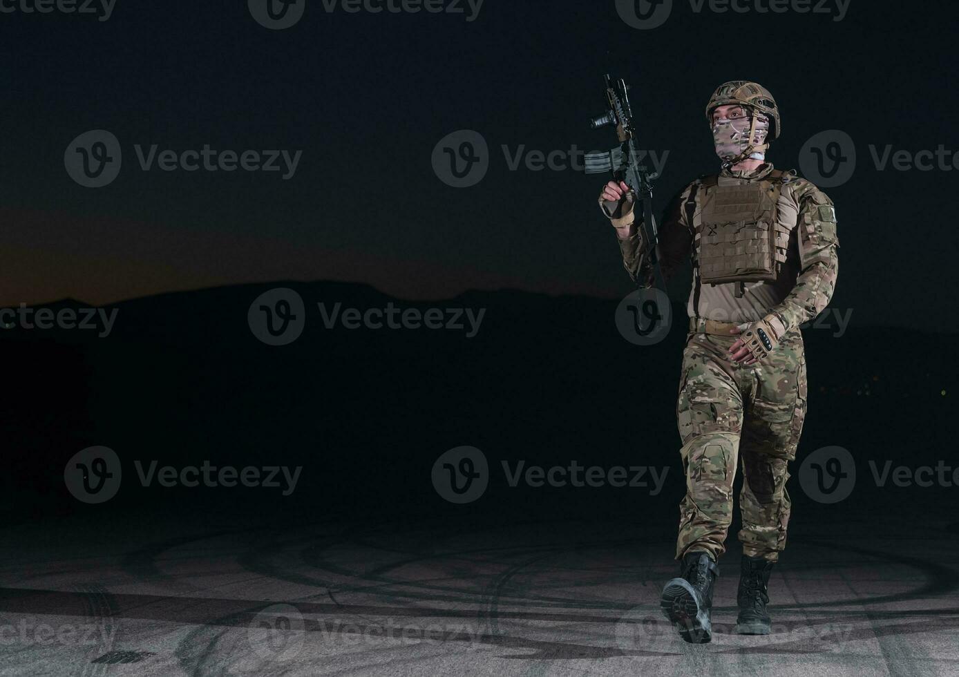 armée soldat dans combat uniformes avec un agression fusil, assiette transporteur et combat casque Aller sur une dangereux mission sur une pluvieux nuit. photo