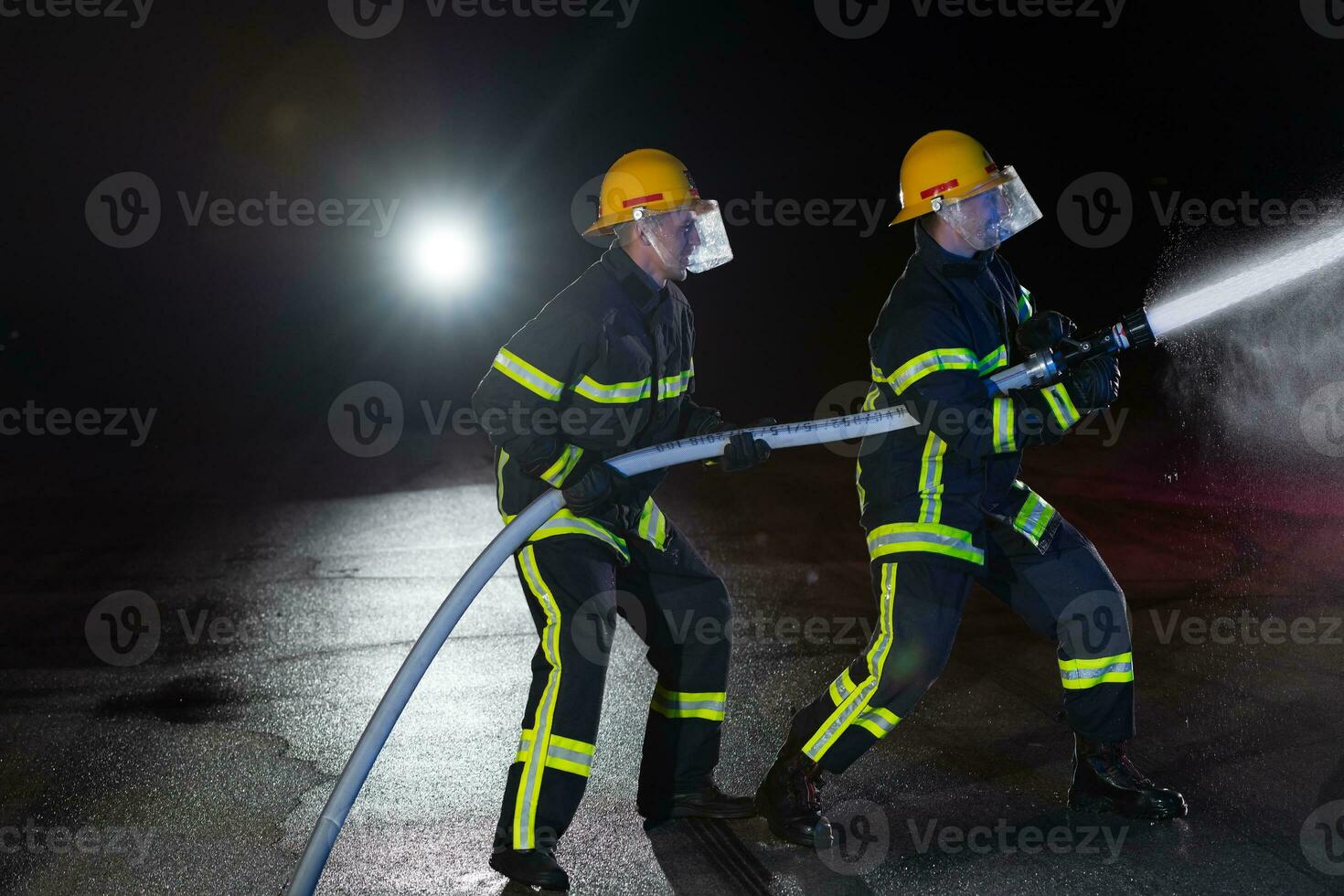 sapeurs pompiers utilisation une l'eau tuyau à éliminer une Feu danger. équipe de pompiers dans le dangereux porter secours mission. photo