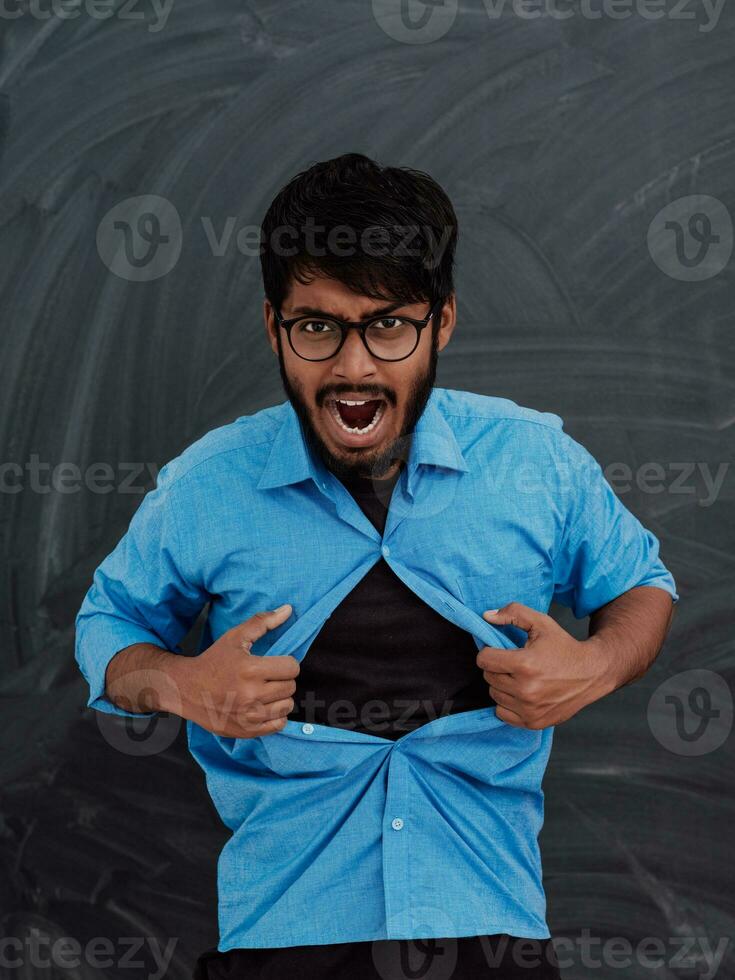 une symbolique photo de un Indien garçon montrant le Superman signe dans de face de le école tableau noir