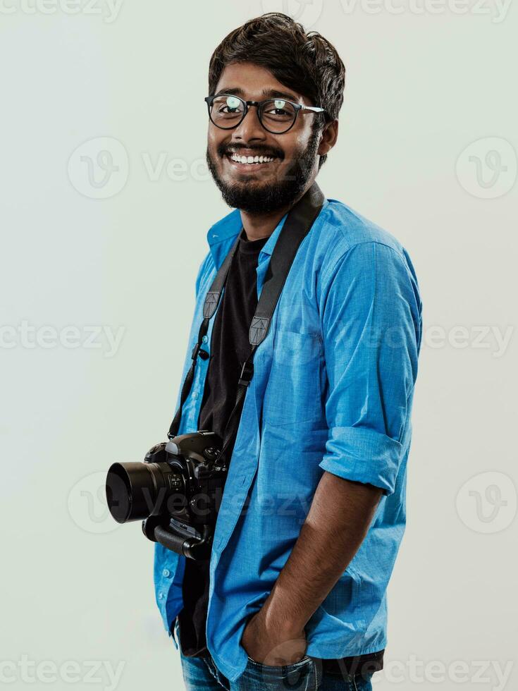 professionnel photographe ayant dslr caméra prise photo.indien homme la photographie passionné prise photo tandis que permanent sur bleu Contexte. studio coup