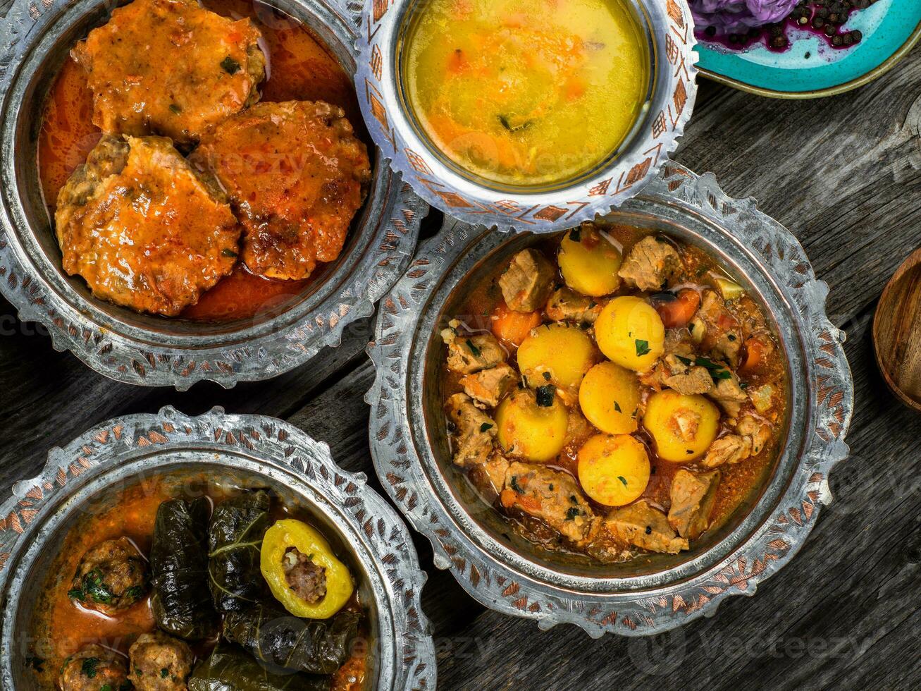 eid mubarak traditionnel Ramadan iftar dîner. assorti savoureux nourriture dans authentique rustique vaisselle sur en bois bleu Contexte. turc bosniaque nourriture Viande kebab, Pita, sarma, klepe, sogan dolma. photo