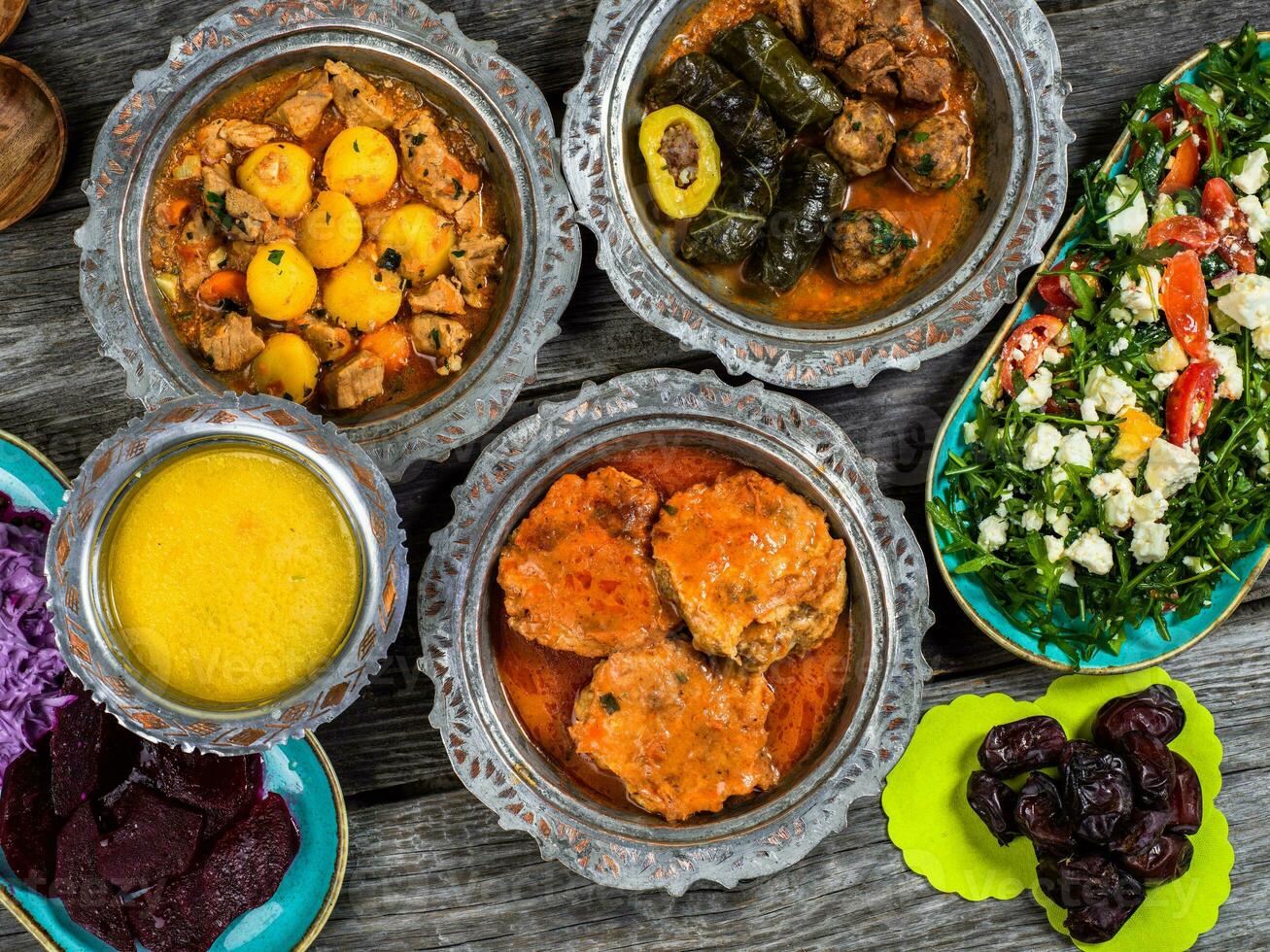 eid mubarak traditionnel Ramadan iftar dîner. assorti savoureux nourriture dans authentique rustique vaisselle sur en bois bleu Contexte. turc bosniaque nourriture Viande kebab, Pita, sarma, klepe, sogan dolma. photo