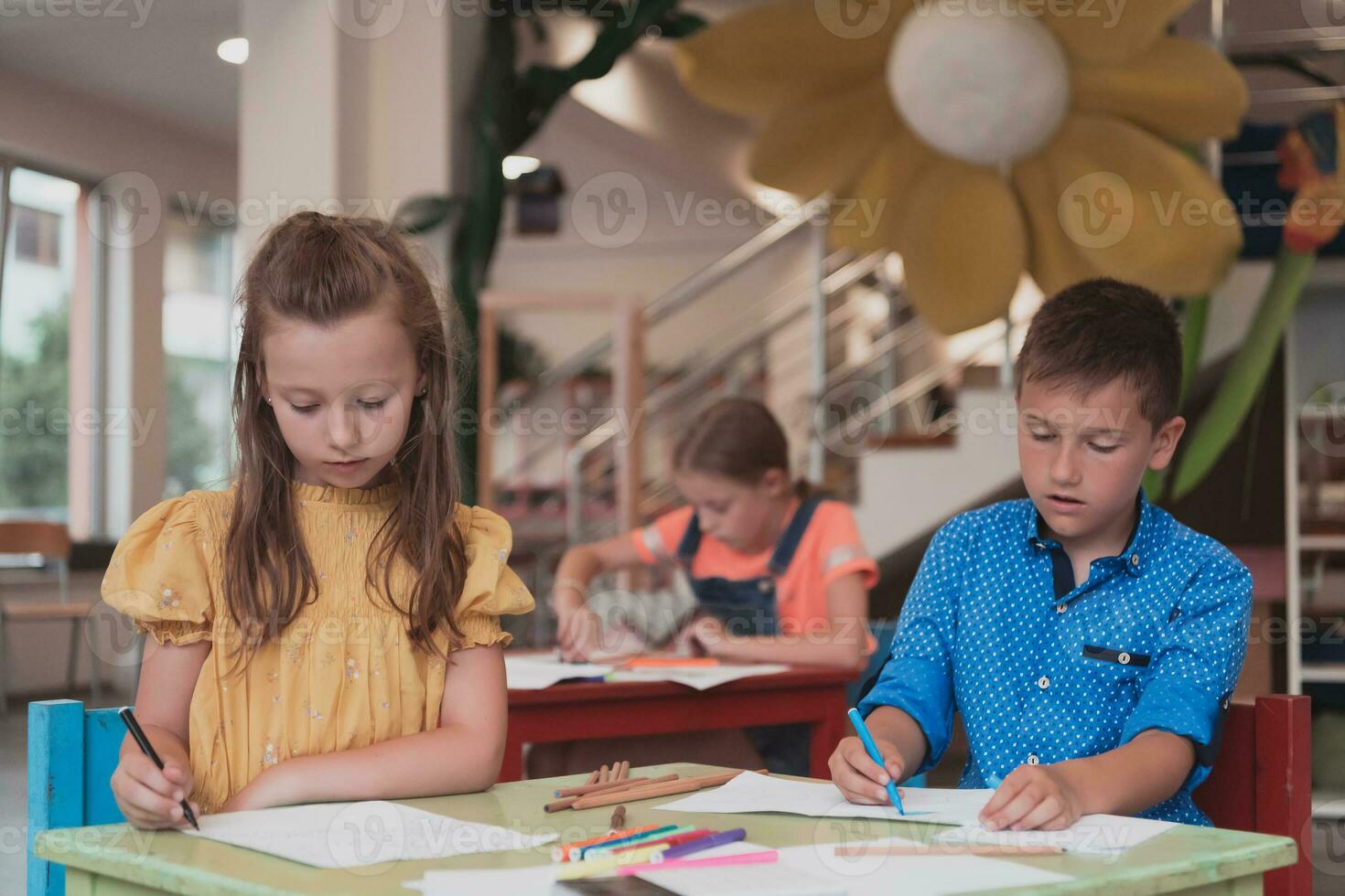 mignonne fille et garçon asseoir et dessiner ensemble dans préscolaire institution photo