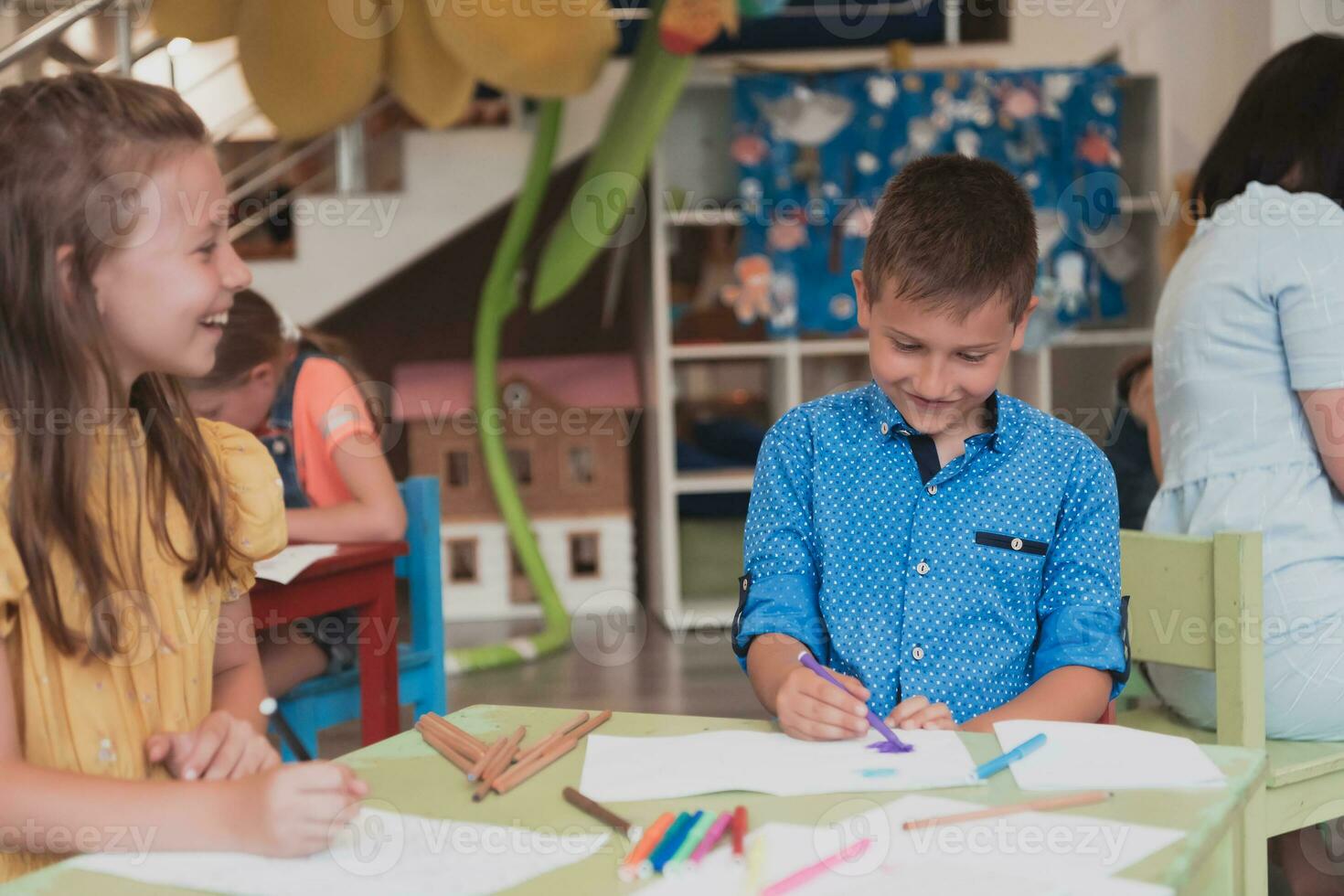 mignonne fille et garçon asseoir et dessiner ensemble dans préscolaire institution photo