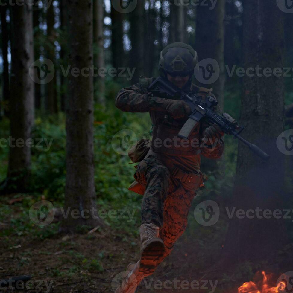 soldat en action la nuit sautant par-dessus le feu photo