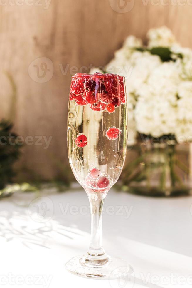 vin mousseux en verre avec des baies de groseille rouge photo