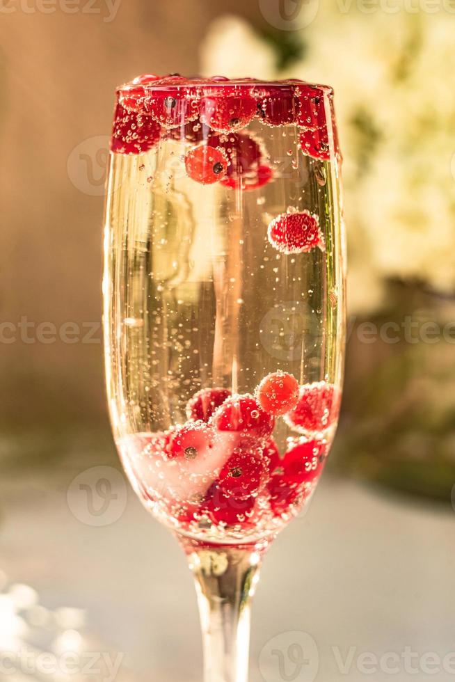 vin mousseux en verre avec des baies de groseille rouge photo