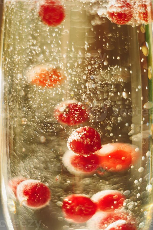 vin mousseux en verre avec des baies de groseille rouge photo