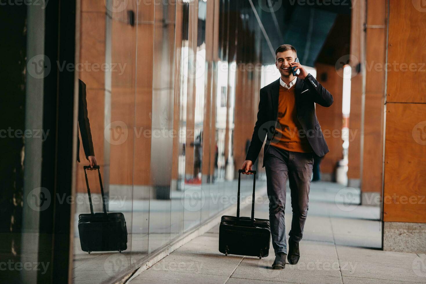 aller au terminal de l'aéroport. voyageur d'affaires confiant marchant dans les rues de la ville et tirant sa valise en buvant du café et en parlant sur un smartphone photo