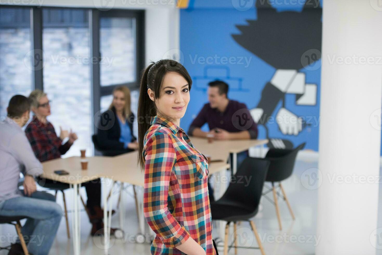 portrait de jeune femme d'affaires au bureau avec l'équipe en arrière-plan photo