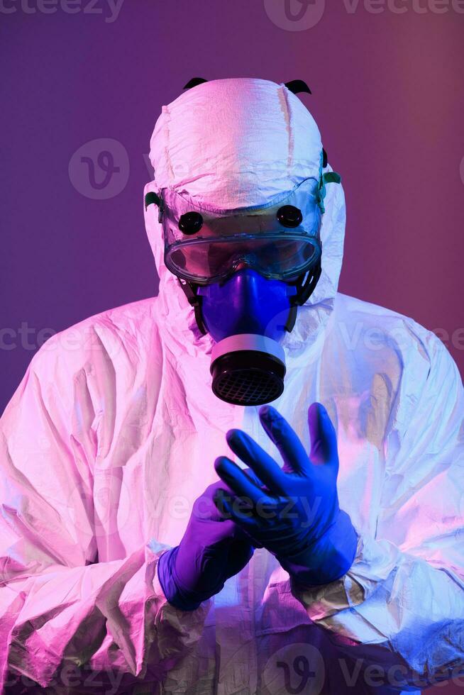 coronavirus covid-19 pandémie. médecin scientifique portant protecteur biologique costume et masque dû à global soins de santé épidémie avertissement et danger Contexte dans bleu et rose néon lumières Contexte. photo