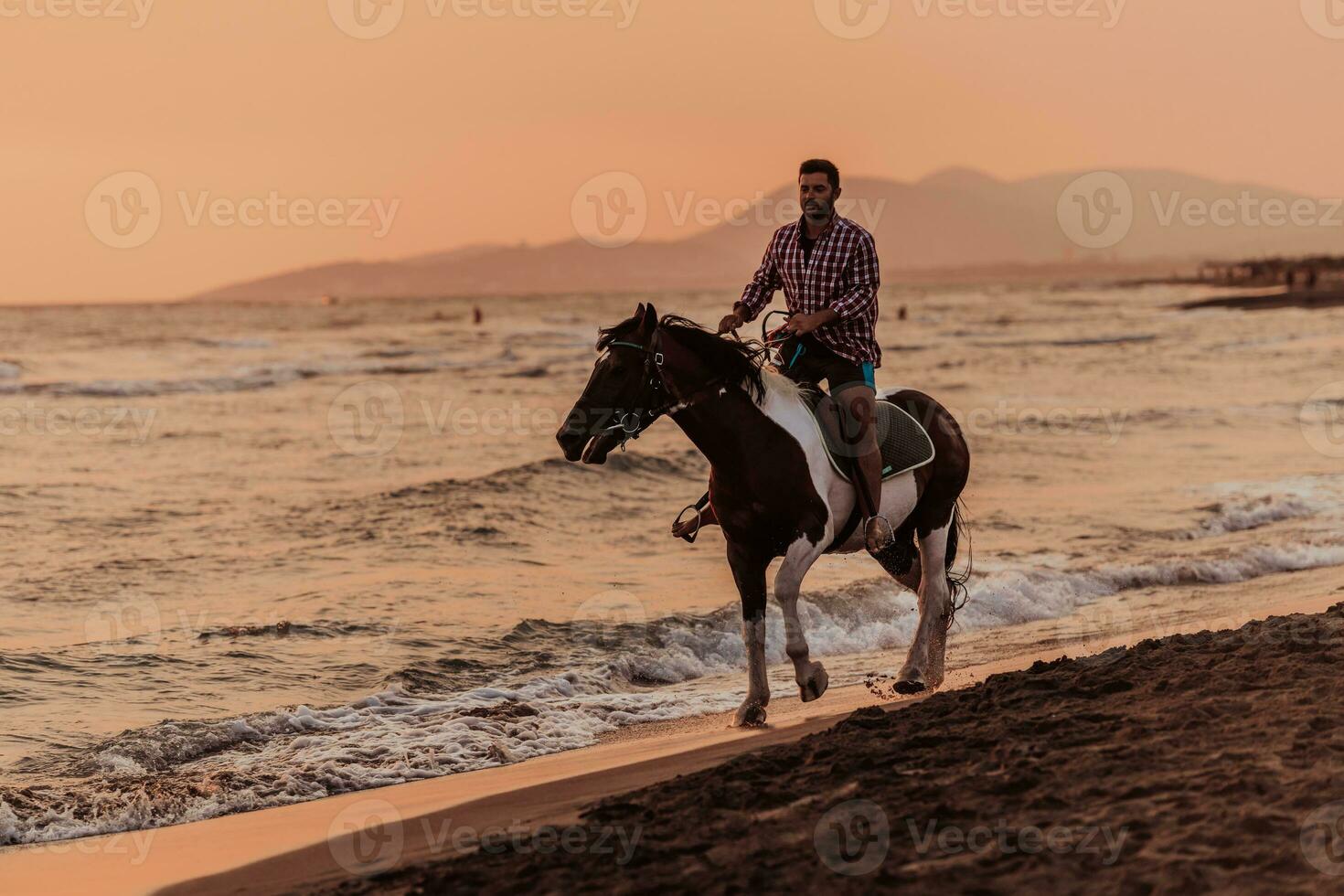 un homme moderne en vêtements d'été aime monter à cheval sur une belle plage de sable au coucher du soleil. mise au point sélective photo