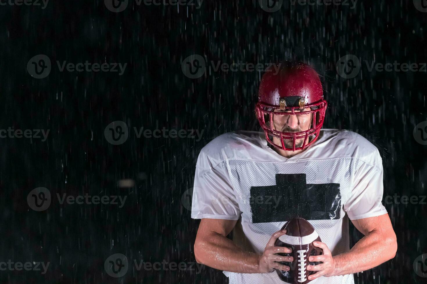 américain Football champ solitaire athlète guerrier permanent sur une champ détient le sien casque et prêt à jouer. joueur en train de préparer à courir, attaque et But atterrissage. pluvieux nuit avec spectaculaire brouillard, bleu lumière photo