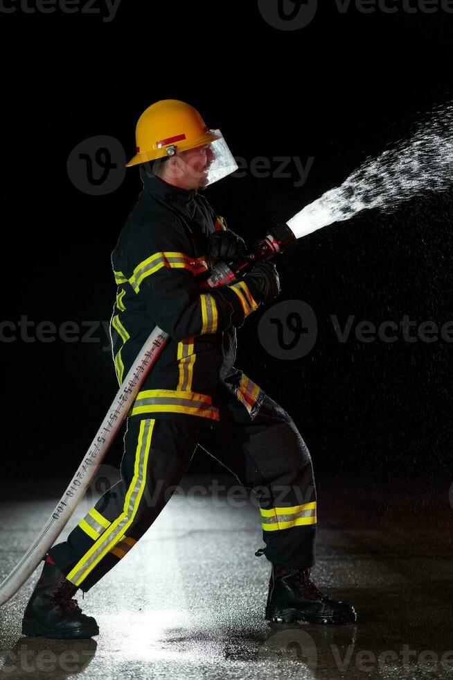 sapeur pompier dans Feu combat opération. portrait de une héroïque pompier dans une protecteur costume et rouge casque dans action pendant lourd pluie. photo