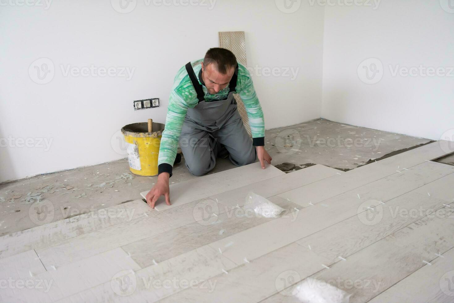 travailleur installant les carreaux en céramique effet bois sur le sol photo