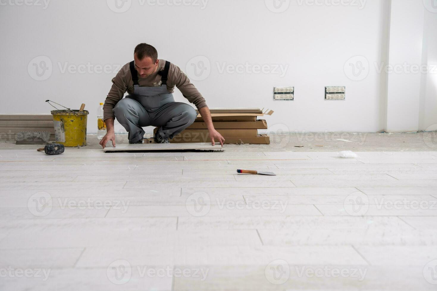 travailleur installant les carreaux en céramique effet bois sur le sol photo