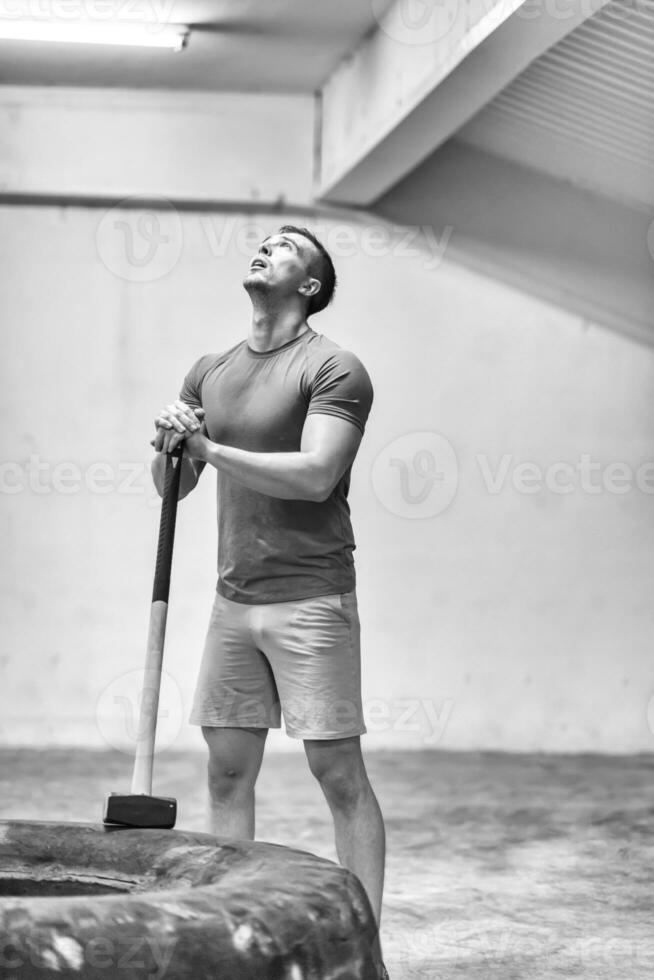 séance d'entraînement d'homme avec le marteau et le pneu de tracteur photo