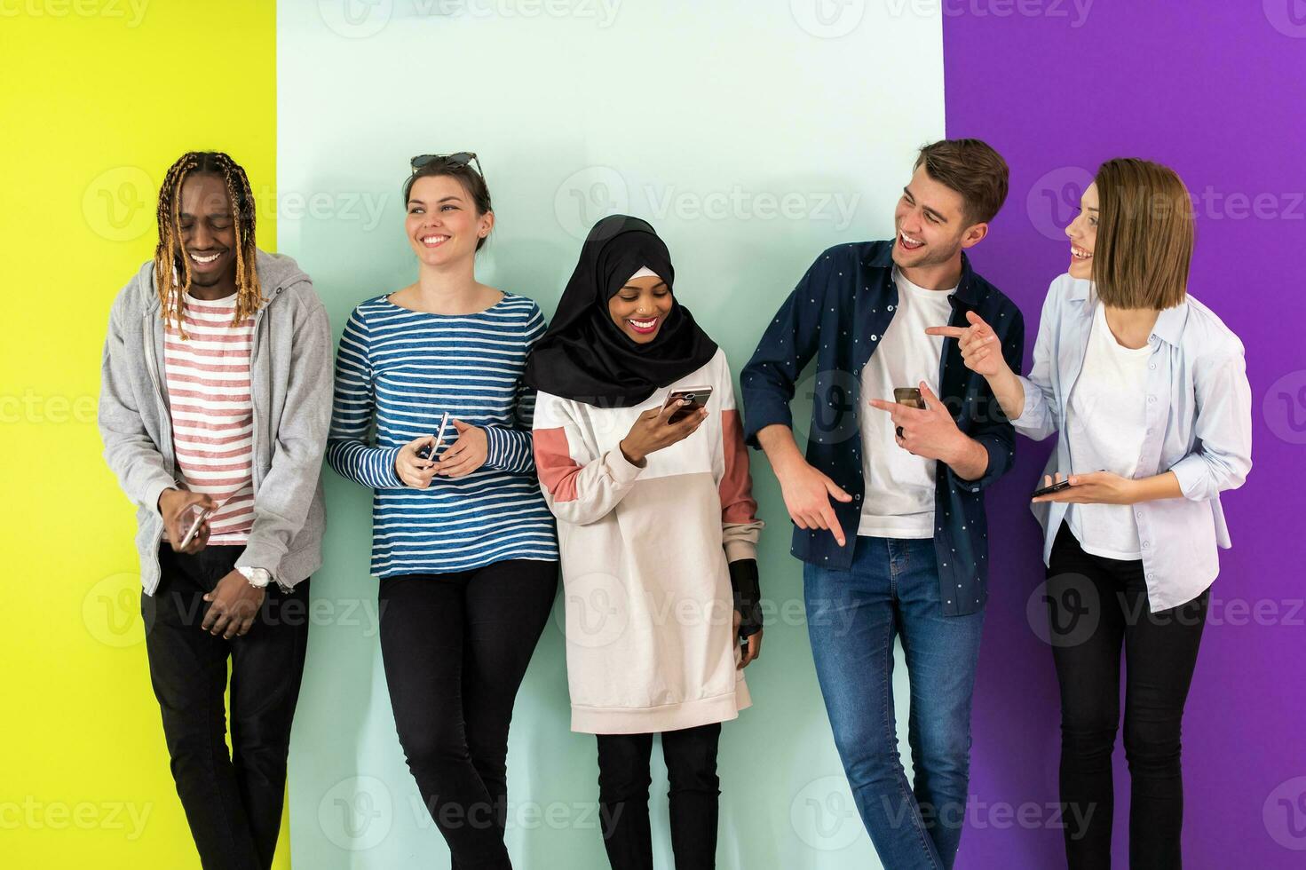 diverse adolescents utilisation mobile dispositifs tandis que posant pour une studio photo dans de face de une coloré Contexte